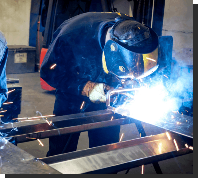 A man welding metal in an industrial setting.